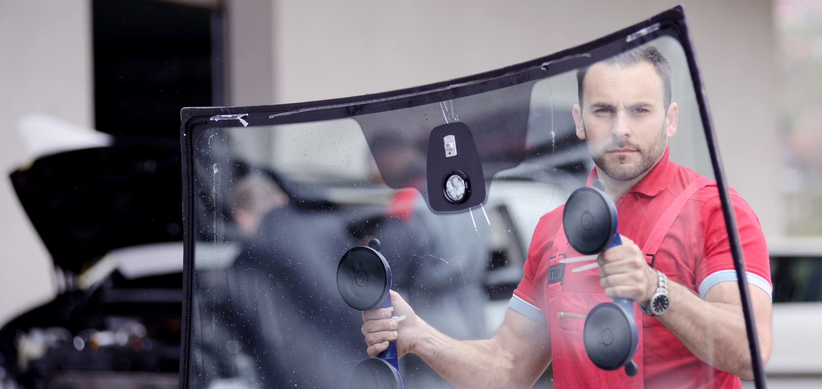 man holding windshield replacement with suction cups